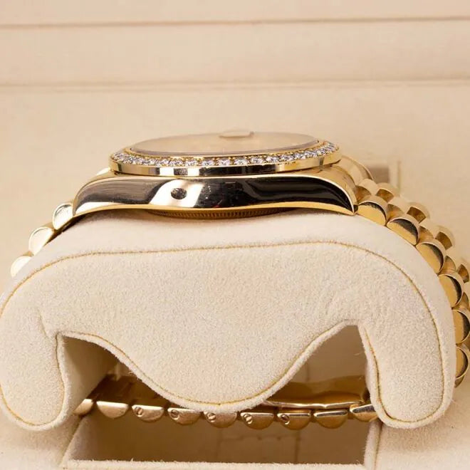 Rolex Day-Date II 218348 18ct Yellow Gold Factory Diamond Bezel & Ruby Dial Gold watch with diamond-studded face on a matching cream cushion