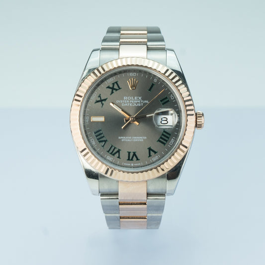 Rolex watch with silver and rose gold band on light blue background