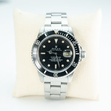 Rolex Submariner 16800 Watch Silver and black watch on a white cushion
