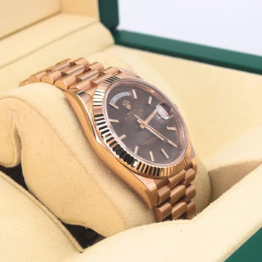Rolex Day-Date 40 228235 Chocolate Motif Dial 18k Everose Gold Watch Rose gold watch with dark face in a display case