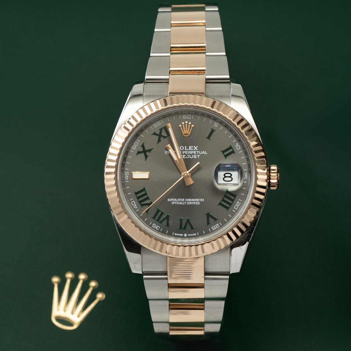 Two-tone Rolex watch with gold and silver band on a green background