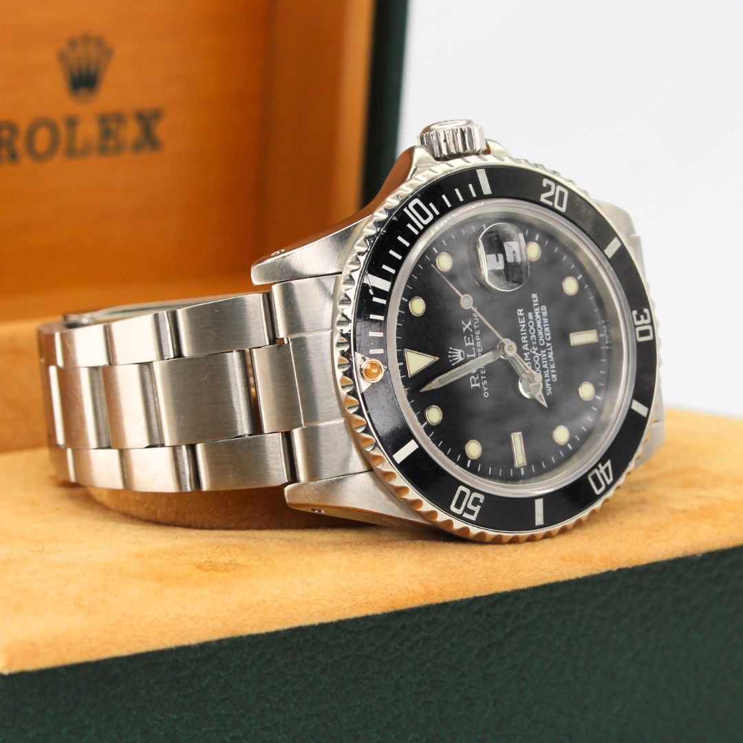 Rolex watch with silver bracelet on a wooden surface