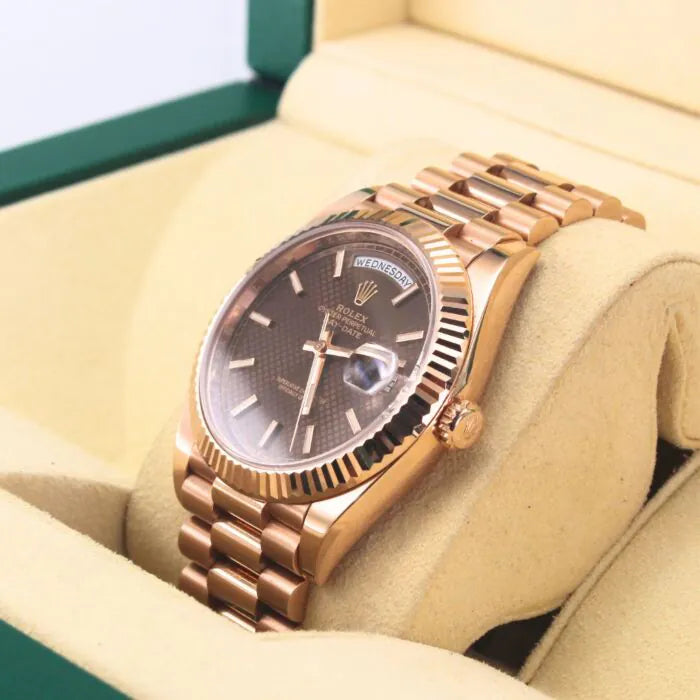 Rolex Day-Date 40 228235 Chocolate Motif Dial 18k Everose Gold Watch Rose gold watch with a dark face in a display case