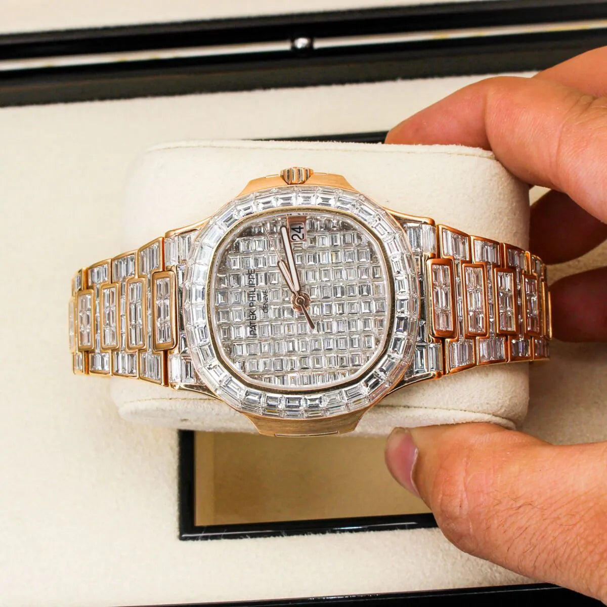 Patek Philippe Nautilus 5711/1R 18K Rose Gold Baguette Diamond Set Luxury diamond-encrusted watch held by a hand with a white box in the background