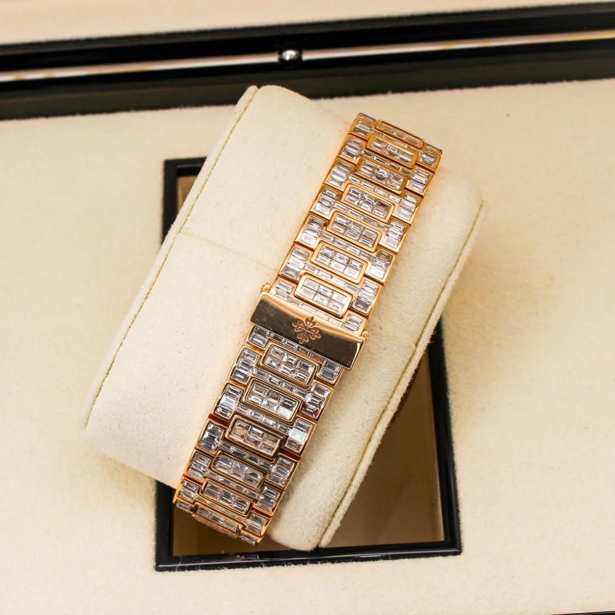 Patek Philippe Nautilus 5711/1R 18K Rose Gold Baguette Diamond Set  Gold bracelet with diamond accents on a beige cushion inside a jewelry box