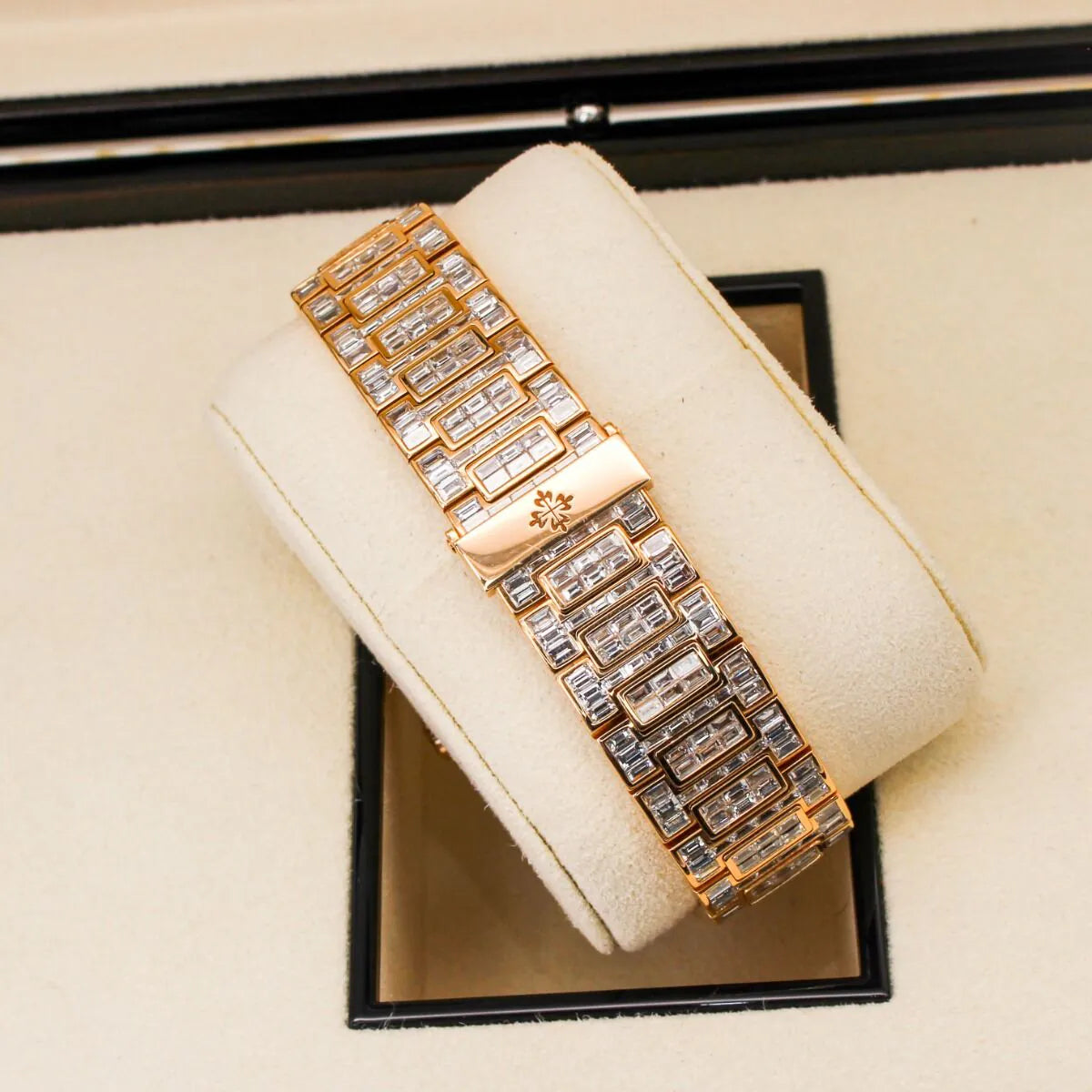 Patek Philippe Nautilus 5711/1R 18K Rose Gold Baguette Diamond Set  Gold bracelet with diamond accents on a white cushion in a jewelry box
