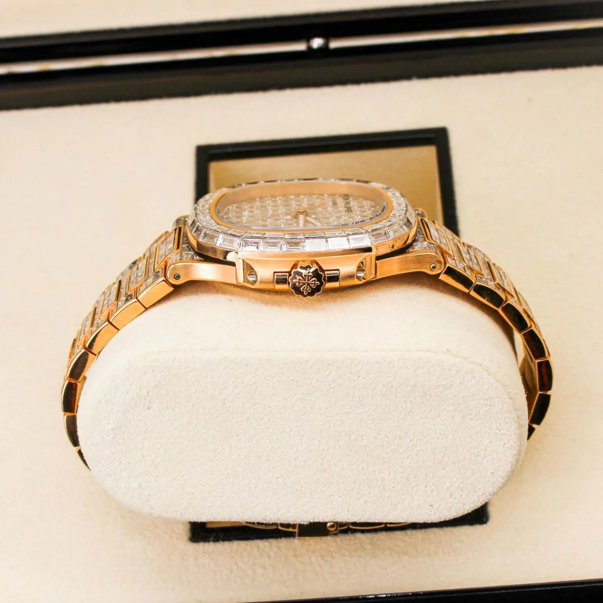 Patek Philippe Nautilus 5711/1R 18K Rose Gold Baguette Diamond Set  Luxury gold watch with diamond accents on a white cushion in a black display case.