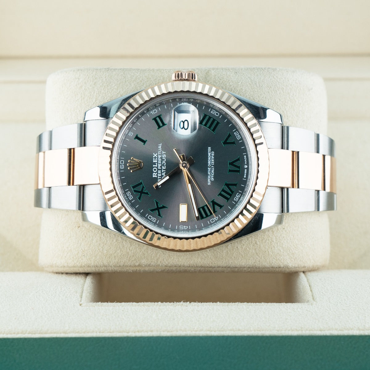 Luxury watch with silver and rose gold case on a beige cushion