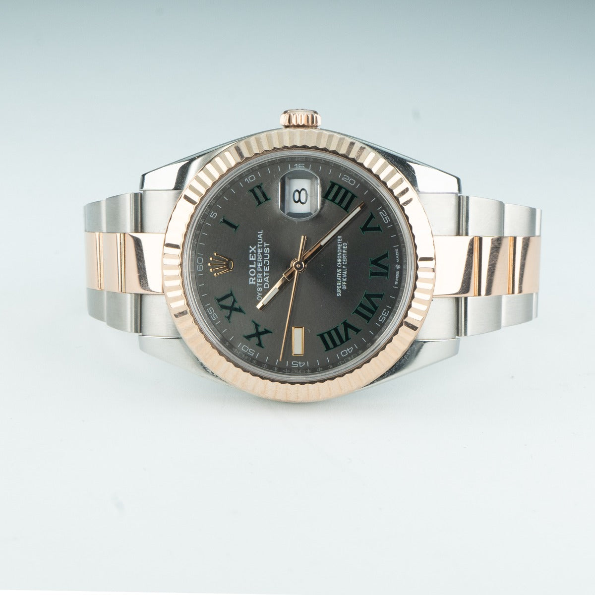 Luxury watch with silver and rose gold band on a light gray background