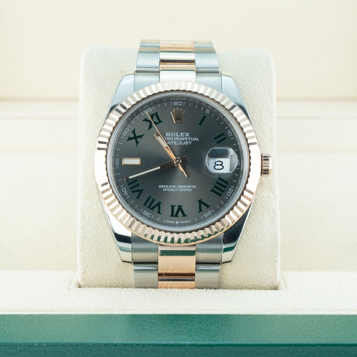 Rolex watch with silver and rose gold band on a white cushion