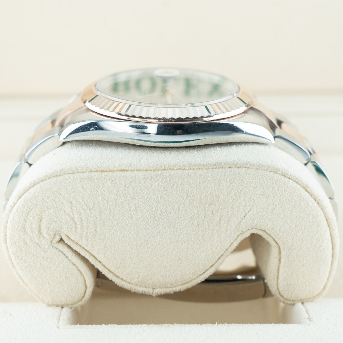 Close-up of a silver watch with 'Rolex' branding on a white cushion
