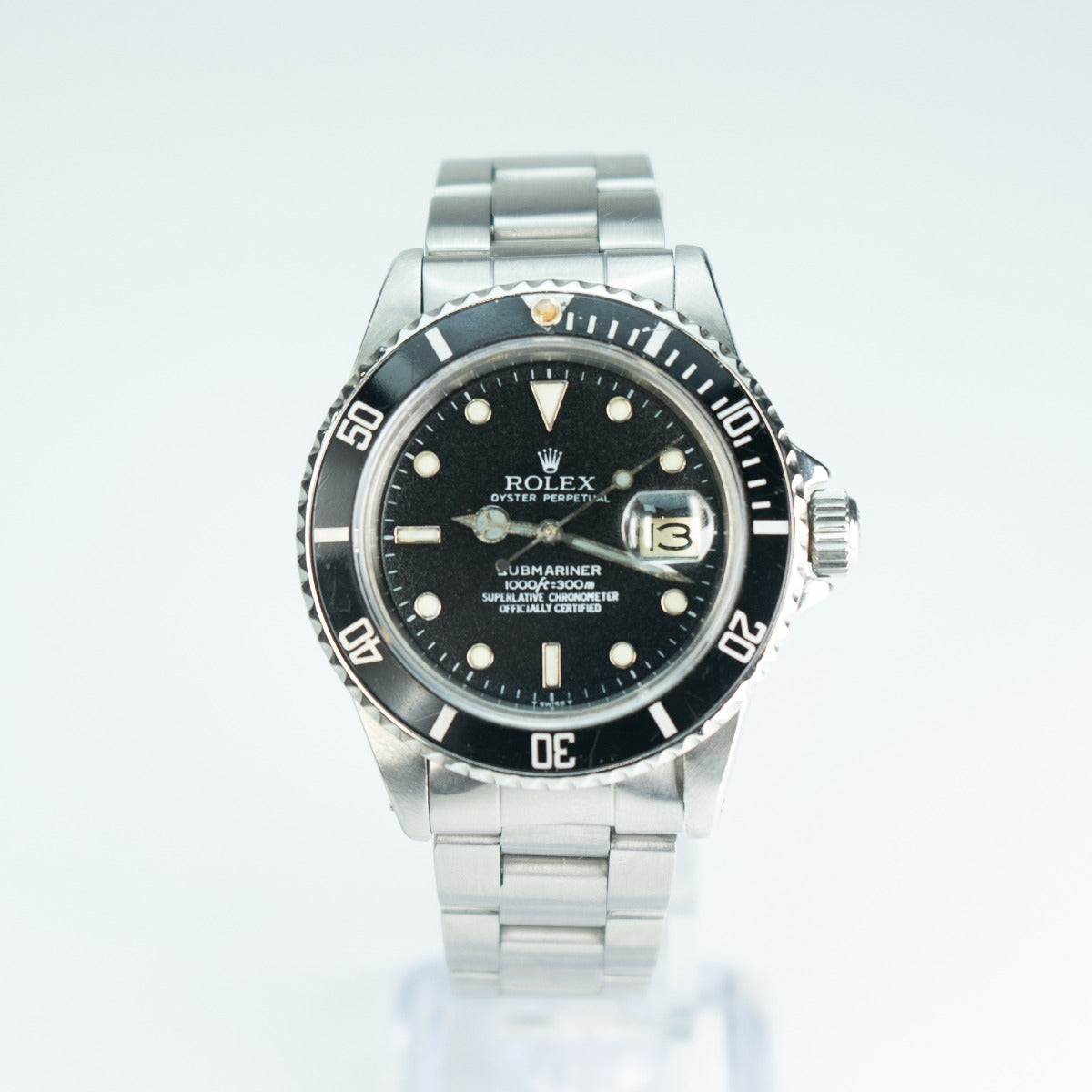 Rolex watch with black dial and silver metal band on a white background
