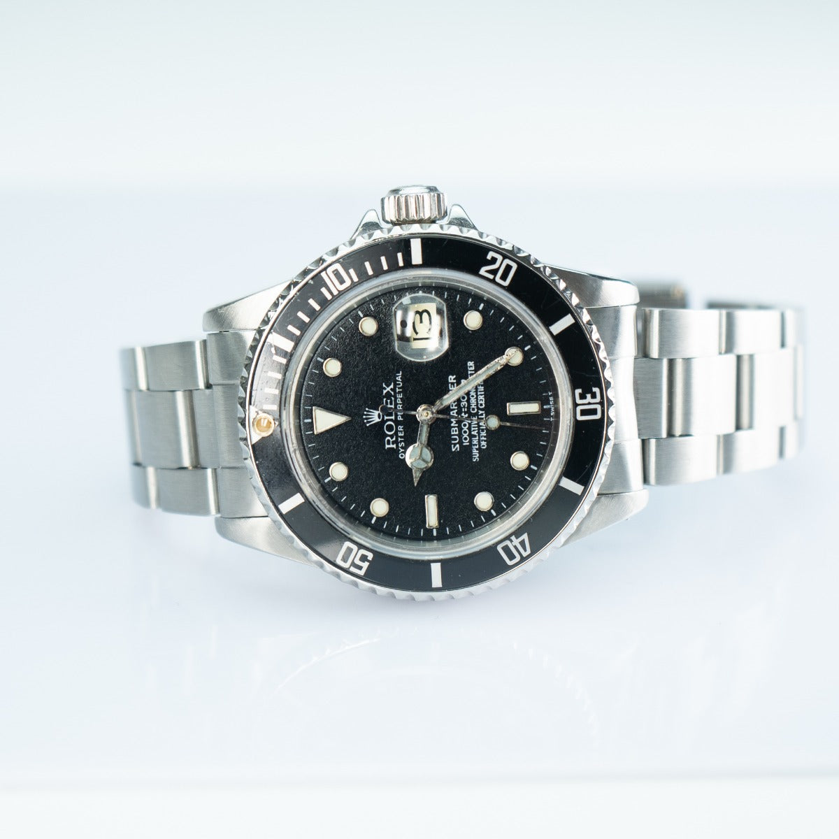 Rolex watch with black dial and silver metal bracelet on a white background