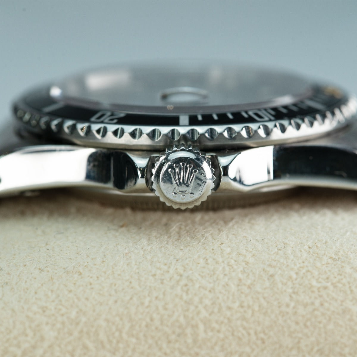 Rolex Submariner 16800 Watch Close-up of a silver watch with a visible brand emblem on a beige surface.
