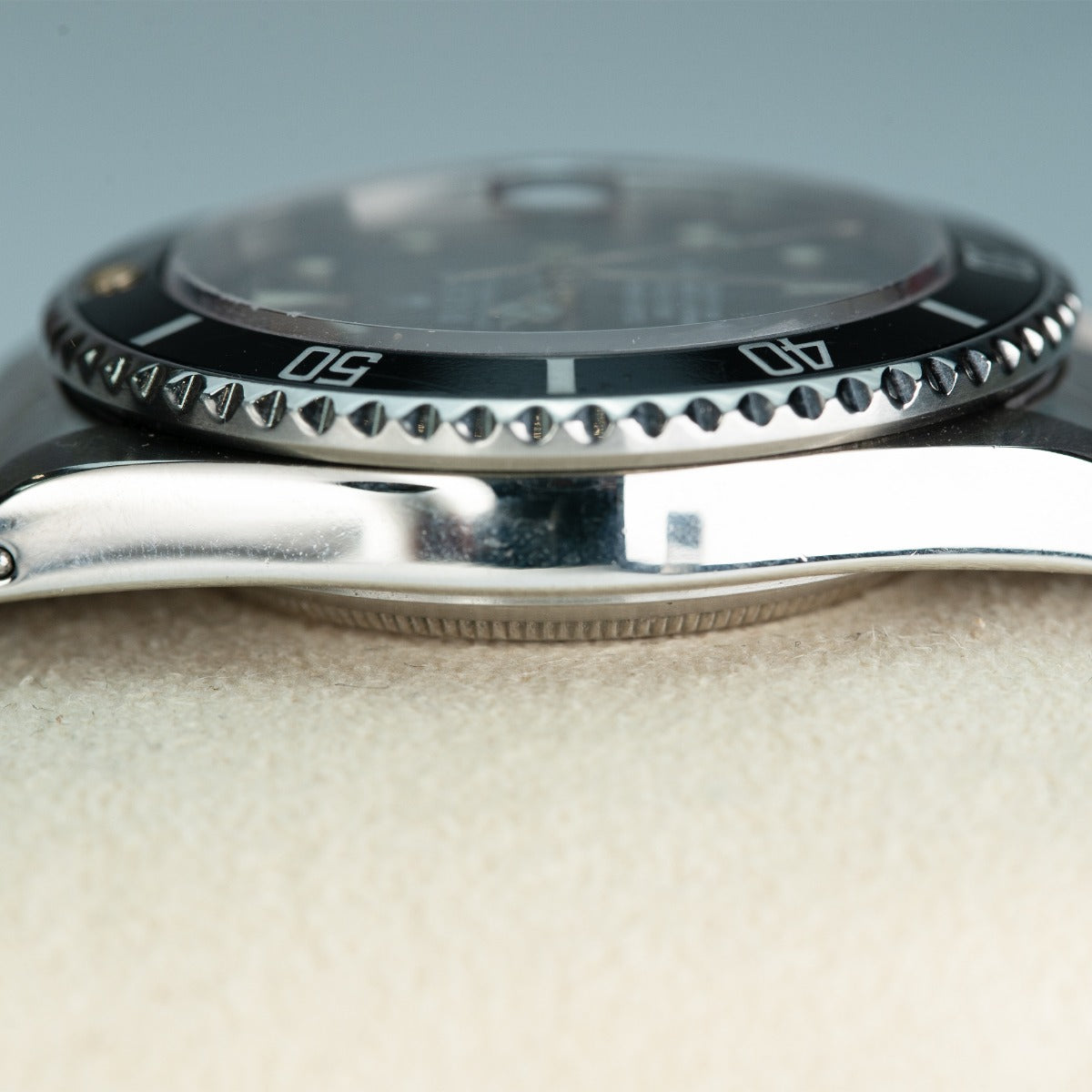 Rolex Submariner 16800 Watch Close-up of a watch with a metallic band on a light background