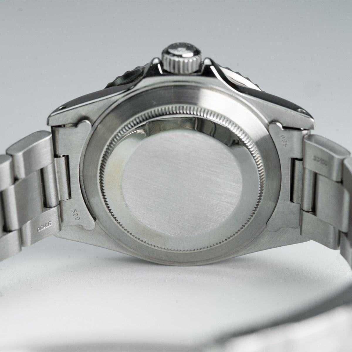 Rolex Submariner 16800 Watch Close-up of a silver watch with a detailed case on a light gray background