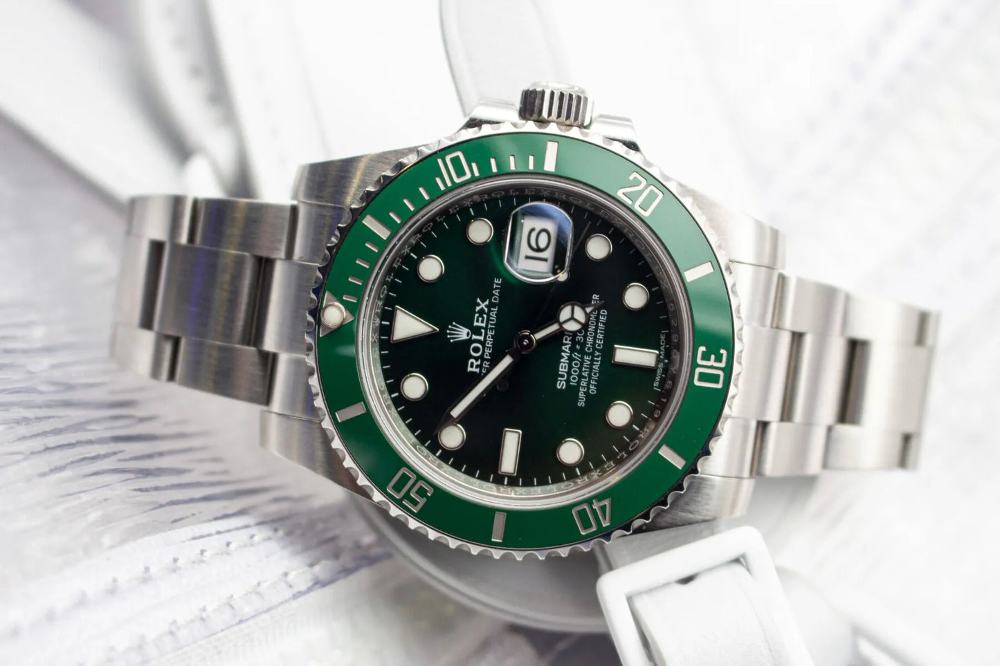 Rolex watch with green bezel and black face on a white background